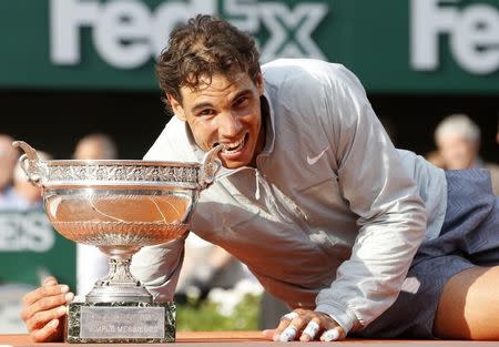 Rafael Nadal of Spain bites the trophy as he poses during the ceremony after defeating Novak Djokovic of Serbia during their men's singles final match to win the French Open Tennis tournament at the Roland Garros stadium in Paris June 8, 2014. REUTERS/Jean-Paul Pelissier