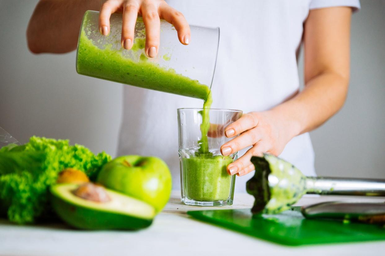 hands juicing green fruits and veggies