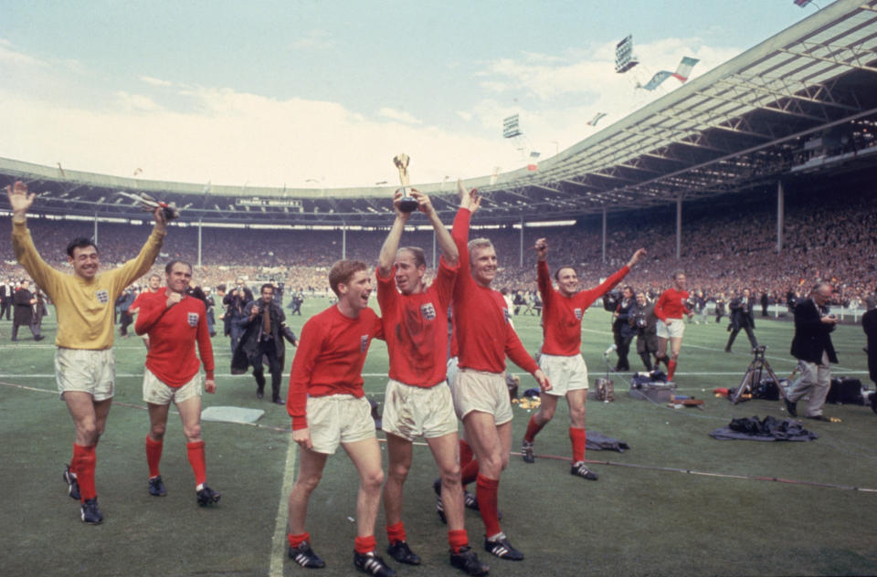 Bobby Charlton raises the Jules Rimet trophy in the air following England's 4-2 victory after extra time over West Germany in the World Cup Final at Wembley Stadium, 30th July 1966. Amongst his team mates celebrating with him are goalkeeper Gordon Banks, Alan Ball on his right and team captain Bobby Moore (1941 - 1993) at his left. (Photo by Hulton Archive/Getty Images)