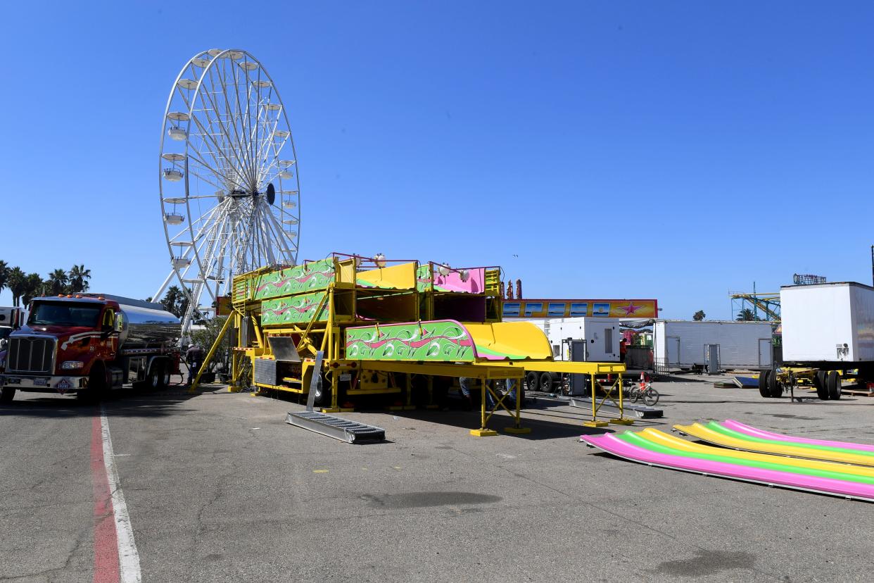 A giant slide sits partially dismantled as workers disassemble rides on the midway at the Ventura County Fairgrounds on Monday, August 15, 2022.