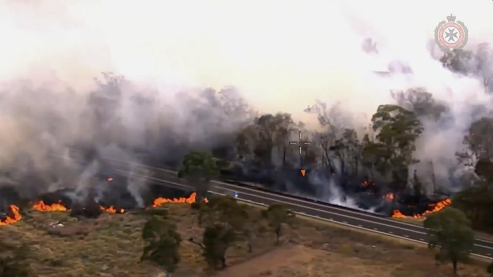 In this image made from video provided by the Queensland Fire And Emergency Services, a wildfire burns an area along a road in Wallangarra, Australia, Tuesday, Oct. 31, 2023. Firefighters have been battling the blaze that has scorched the Queensland state town of Tara for more than a week. (Queensland Fire And Emergency Services via AP)