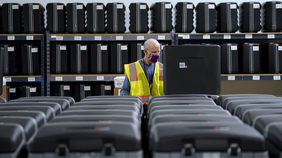 FILE - In this Sept. 3, 2020, file photo, a worker prepares tabulators for the upcoming election at the Wake County Board of Elections in Raleigh, N.C. The coronavirus pandemic is forcing millions of American voters worried about their health to scramble to vote by mail for the first time. But a requirement in a handful of states, including presidential battleground North Carolina and Wisconsin, that a witness or notary public sign a ballot envelope is tripping up some voters early. (AP Photo/Gerry Broome, file)