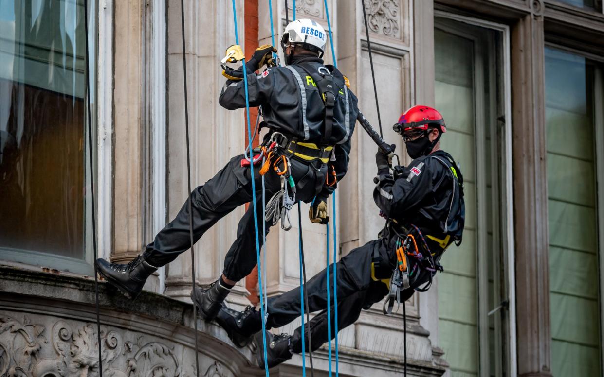 The special forces veterans abseil down the front of the building as the squatters are evicted - James Linsell-Clark/SWNS