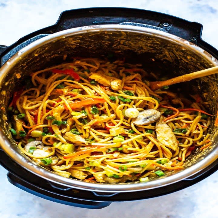 A slow cooker filled with chicken and vegetable lo mein