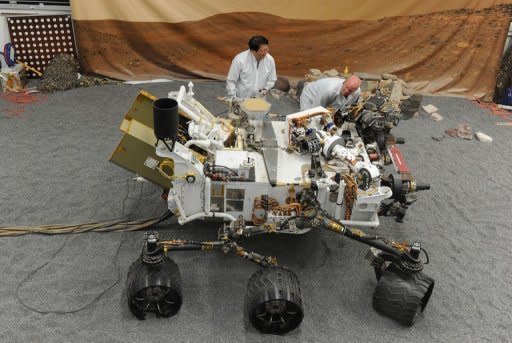 Jet Propulsion Laboratory (JPL) engineers examine a full size engineered model of the Mars rover Curiosity, on August 2. About 36 hours after the US space agency's landed its $2.5 billion rover on Mars, NASA released Tuesday what it called a "crime scene" aerial shot of where the parachute, heat shield and rover came down