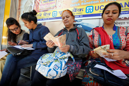 Women count 500 and 1000 Indian rupee banknotes before depositing them at a bank in Chandigarh, November 10, 2016. REUTERS/Ajay Verma