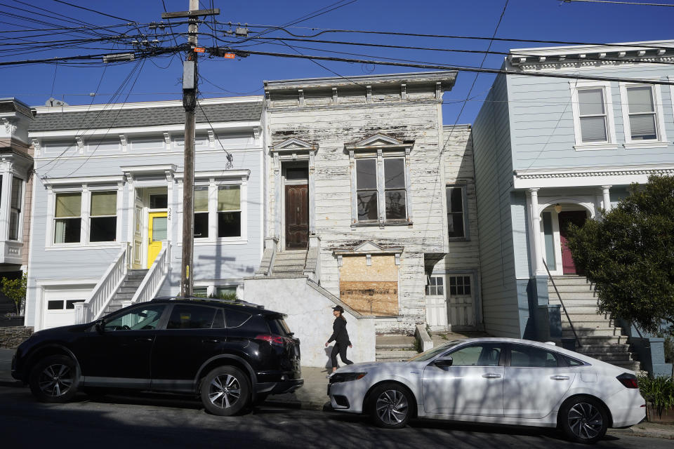 A pedestrian walks past a recently sold Victorian home in San Francisco, Friday, Jan. 14, 2022. The decaying, 122-year-old Victorian marketed as "the worst house on the best block" of San Francisco recently sold for nearly $2 million — an eye-catching price that the realtor said was the outcome of overbidding in an auction. (AP Photo/Jeff Chiu)