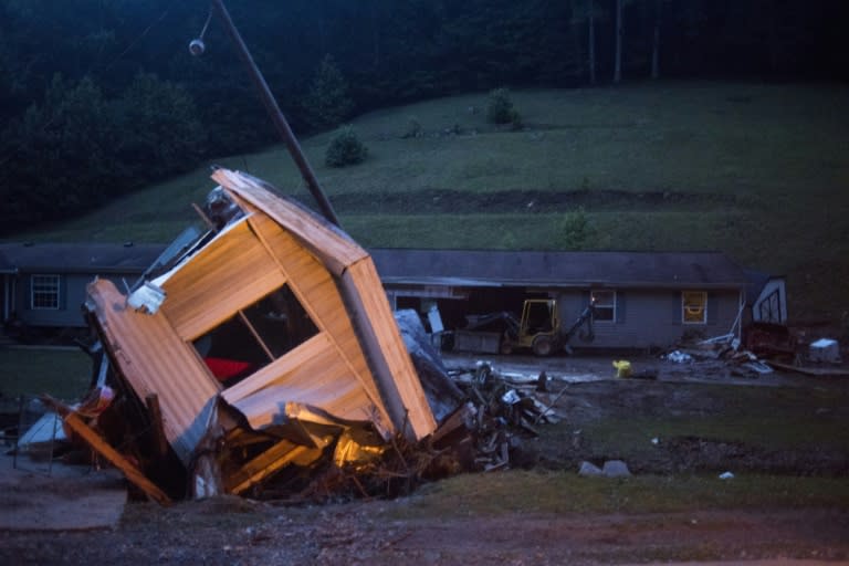 A mobile home lies on its side off the road in front of a home after it was washed away by a flash flood along Jordan Creekon in Elkview, West Virginia on June 25, 2016