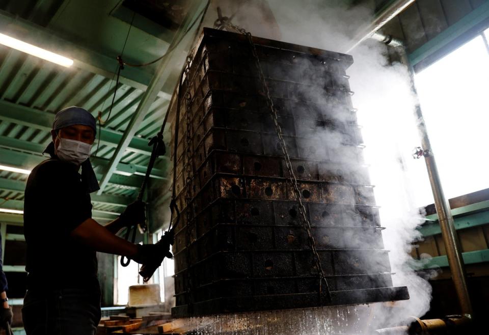 A worker carries baskets containing boiled fillets of katsuo to make katsuobushi at the Takeuchi Ltd factory (Reuters)