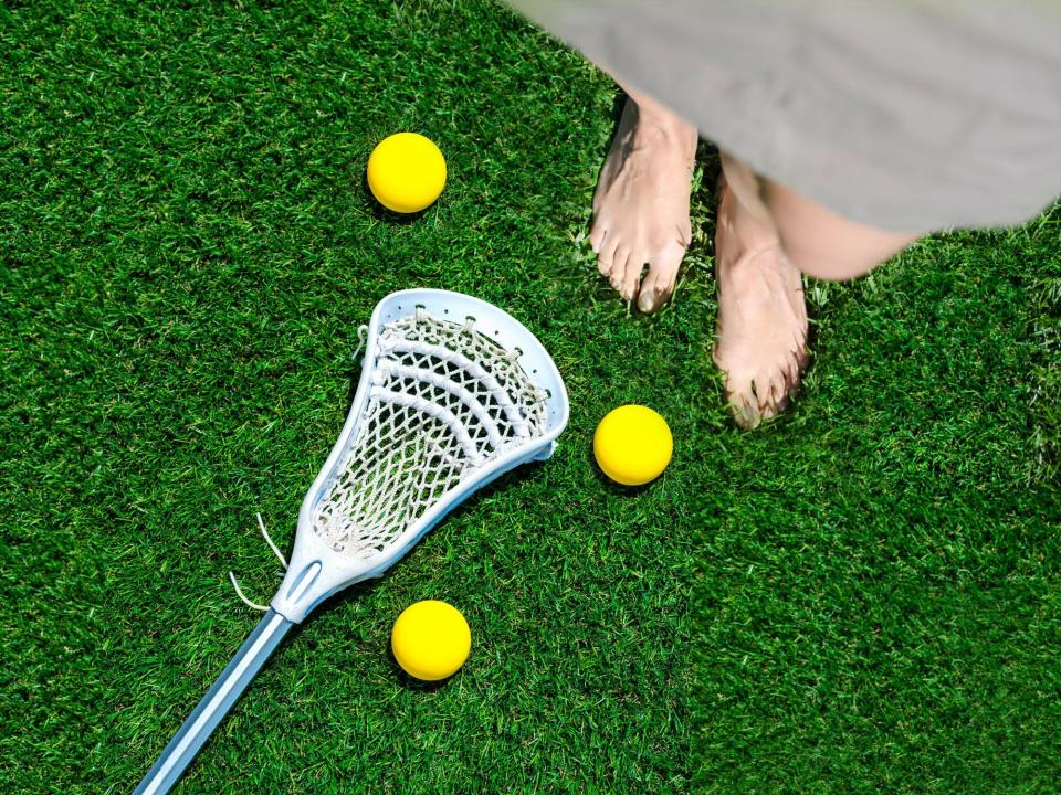 Low Section Of Woman Standing On Green Grass with lacrosse balls