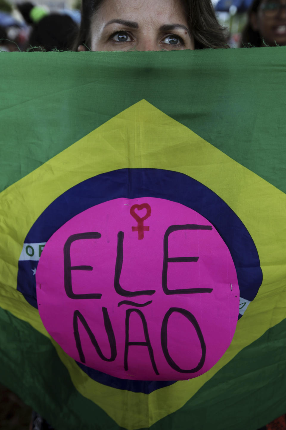 A woman shows a Brazilian flag with text written on it that reads in Portuguese "Not him" during a protest called "Women against Bolsonaro," in Brasilia, Brazil, on Saturday, Oct. 20, 2018. Women and left-wing militants held protests across the country against the right-wing presidential candidate Jair Bolsonaro. (AP Photo/Eraldo Peres)