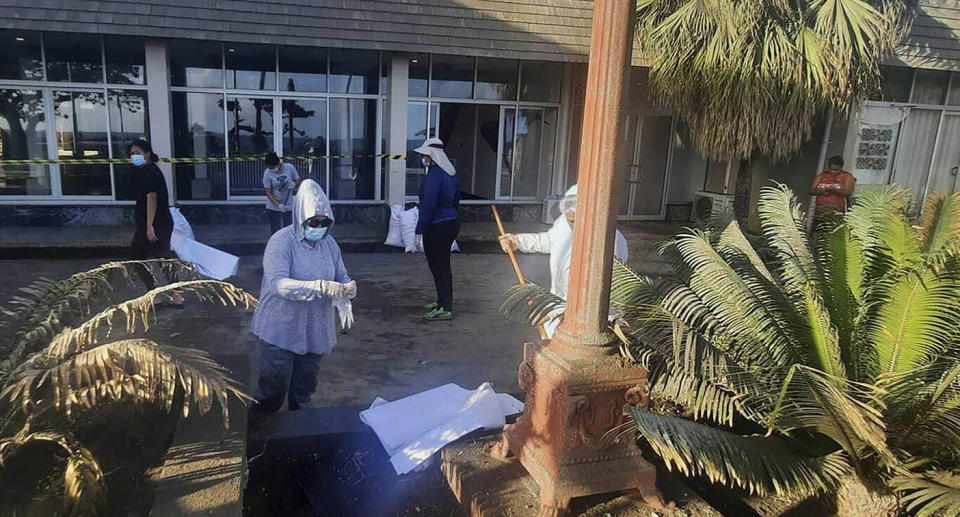 People wearing masks and gloves cleaning up outside a building in Nuku'alofa, Tonga.