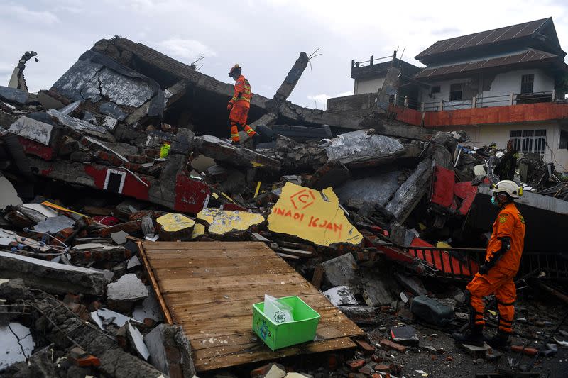 Search and rescue personnel inspect a collapsed building following an earthquake in Mamuju