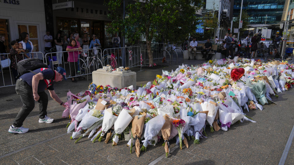 A man places flowers as a tribute near a crime scene at Bondi Junction in Sydney, Monday, April 15, 2024, after several people were stabbed to death at a shopping on April 13. Australian police are examining why a lone assailant who stabbed several people to death in a busy Sydney shopping mall and injured more than a dozen others targeted women while avoiding men, a police commissioner said on Monday. (AP Photo/Mark Baker)