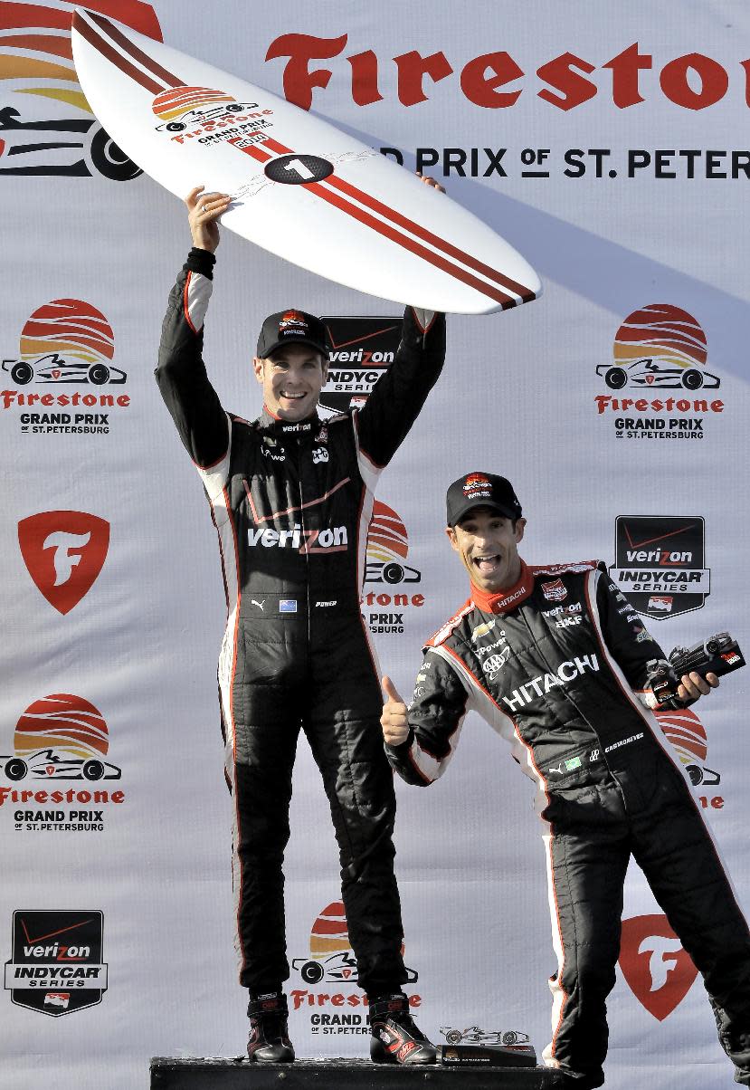 Third-place finisher Helio Castroneves, right, of Brazil, jumps in the photo as Will Power, of Australia, poses with his surfboard after Power won the IndyCar Grand Prix of St. Petersburg auto race, Sunday, March 30, 2014, in St. Petersburg, Fla. (AP Photo/Chris O'Meara)