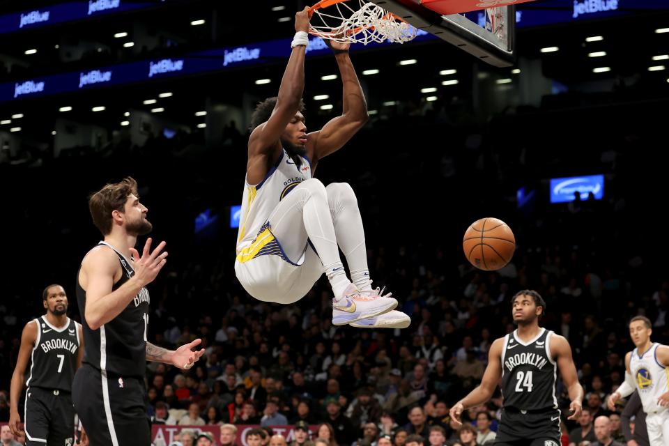 Golden State Warriors center James Wiseman hangs on the rim after dunking against the Brooklyn Nets during the second quarter at Barclays Center, Dec. 21, 2022 in Brooklyn, New York.