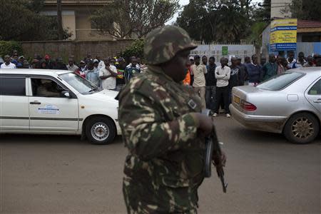 A soldier patrols as onlookers watch from a distance the security operation at the Westgate Shopping Centre, where gunmen are holding hostages, in Nairobi September 22, 2013. REUTERS/Siegfried Modola