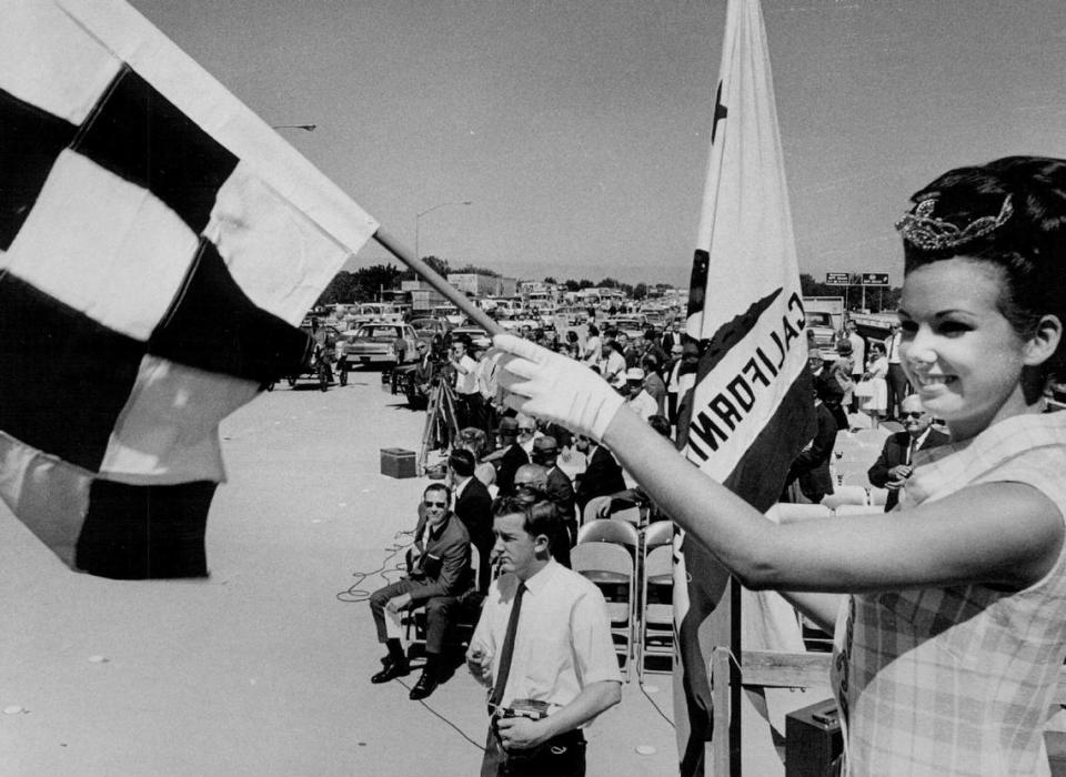 A starting flag is waved by Miss Sacramento Patti Smith to start traffic through the interchange connecting the W-X freeway to the freeway that runs between 29th and 30th streets during the official dedication ceremonies in 1968.