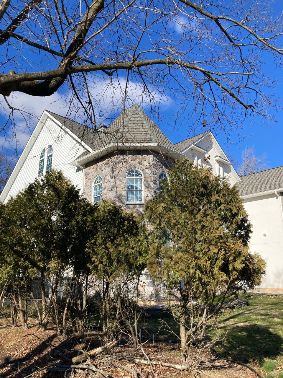 The stone turret of the Levittown mansion looms over privacy hedges in Melissa Andrusko's yard.