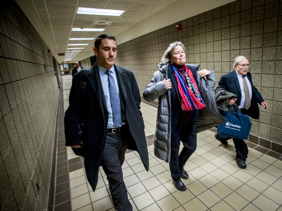 Dr. Eden Wells, center, puts her jacket on as she leaves the court house alongside her defense attorneys Steve Tramontin, left, and Jerold Lax after a hearing Friday, Dec. 7, 2018, at Genesee District Court in downtown Flint, Mich. Wells, Michigan's chief medical executive, will stand trial on involuntary manslaughter and other charges in a criminal investigation of the Flint water crisis, a judge ruled Friday. (Jake May/The Flint Journal via AP)