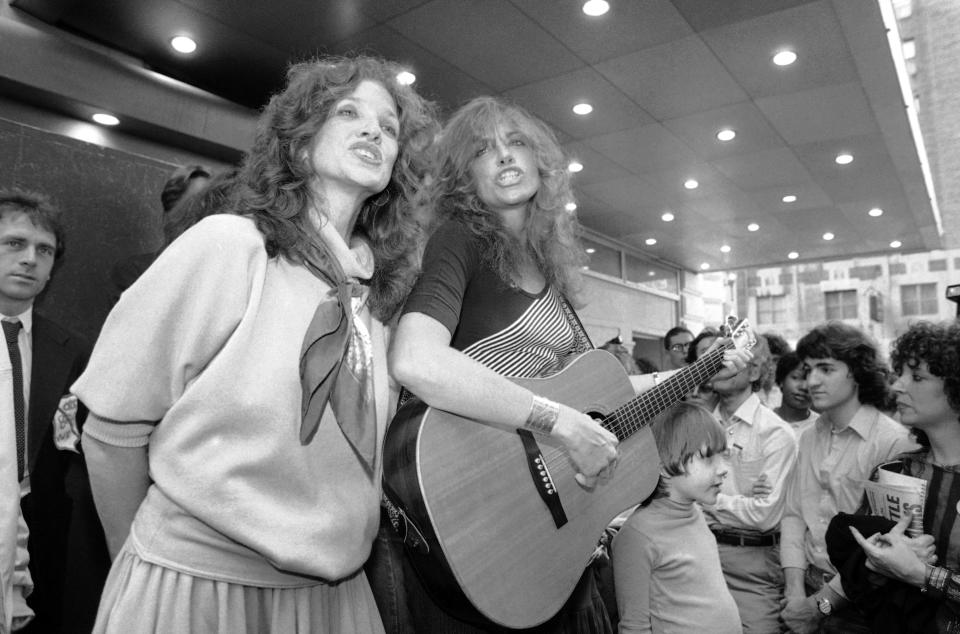 FILE - Lucy Simon, left, and her sister Carly Simon sing in Broadway's Shubert Alley in New York, on June 9, 1982. Lucy Simon, the composer who received a Tony nomination in 1991 for her work on the long-running Broadway musical “The Secret Garden,” died Thursday at her home in Piedmont, N.Y., after a long battle with breast cancer. She was 82. (AP Photo/Nancy Kaye, File)