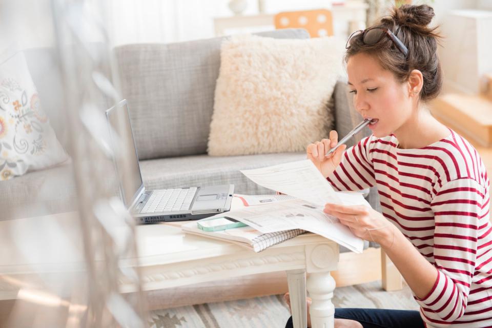 Woman working at laptop on personal finances to manage cost of living.