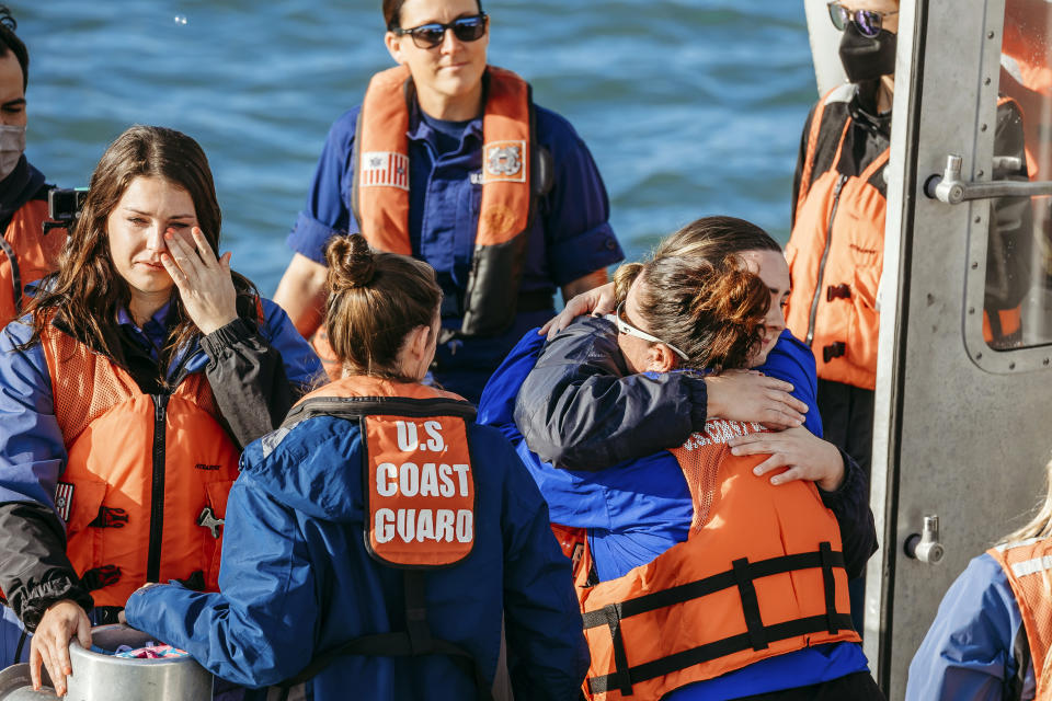 Clearwater Marine Aquarium vice president of zoological care Kelly Martin, right back to camera, and animal care specialist Brie Alessi embrace after aquarium staff released the ashes of Winter the Dolphin into the Gulf of Mexico from the back of a U.S. Coast Guard response boat, Thursday, Jan. 13, 2022, of the coast of Clearwater, Fla. Winter, a prosthetic-tailed dolphin that starred in the “Dolphin Tale” movies, died on Nov. 11, 2021, at age 16 of an inoperable intestinal problem. (Clearwater Marine Aquarium via AP)