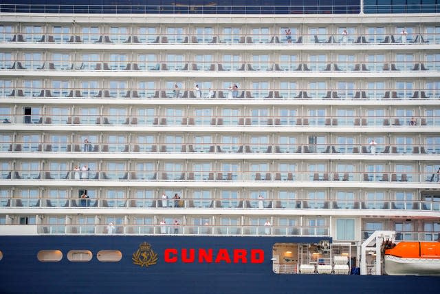 Passengers look out from their cabins on the Queen Anne