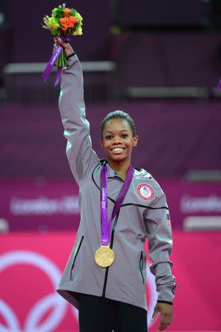 <p>EMMANUEL DUNAND/AFP via Getty</p> Gabby Douglas poses on the podium during the London 2012 Olympics