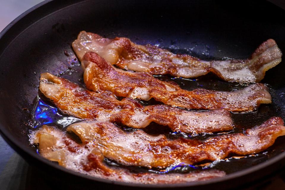 Bacon fries in a pan.