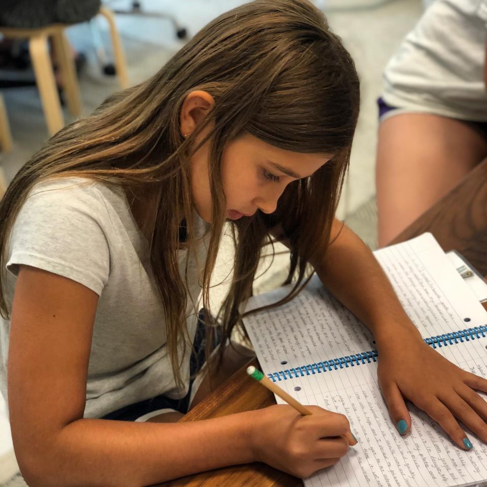 In this June 14th, 2018 photo provided by Syed Ali Haider, 11-year-old Lila Gonzalez focuses on her short story during Austin Bat Cave's week-long Fiction Writing summer camp in Austin, Texas. Educators say teaching critical and creative writing is just as important as strong reading and is too often overlooked. "When students own their voices and tell their stories, they become not only stronger and more confident writers, but also stronger and more confident individuals," says Ali Haider, executive director of Bat Cave, the Austin-based creative writing center. (Syed Ali Haider via AP)