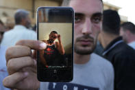 A Palestinian man Salim al-Jar, shows through his mobile phone a picture of his brother Wissam who is one of the missing bodies who were on a boat carrying migrants from Lebanon that sank in Syrian waters, as he waits with other victims relatives, at Arida border crossing point between Lebanon and Syria, north Lebanon, Sept. 23, 2022. Syria's health minister says several people have been killed from a boat that sank migrants from Lebanon off Syria's coast. The incident is the deadliest since a surging number of Lebanese, Syrians, and Palestinians have tried to flee crisis-hit Lebanon by sea to Europe. (AP Photo/Bilal Hussein)