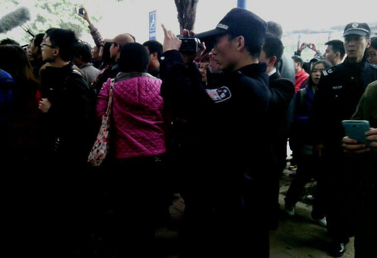 A policeman films as demonstrators call for press freedom in support of journalists from the Southern Weekend newspaper outside the company's office building in Guangzhou, south China's Guangdong province on January 8, 2013