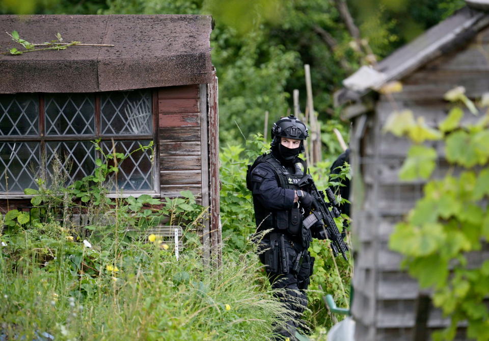 Armed police search an allotment site in Enfield during the hunt for Kyle Clifford. (SWNS)