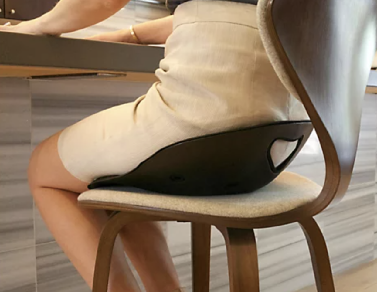 Person sitting in a black posture seat at a desk