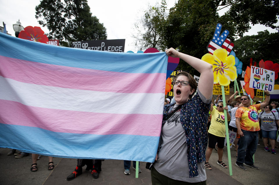 FILE - A supporter for the transgender community holds up a flag in front of counter-protesters at the city's Gay Pride Festival, Oct. 12, 2019, in Atlanta. Courts nationwide are delivering a mixed verdict on the future of state laws restricting gender-affirming medical care for transgender youth, as legal battles ramp up over the historic wave of bans enacted in 2023. (AP Photo/Robin Rayne, File)