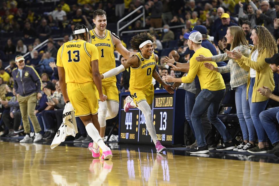 Michigan guard Dug McDaniel, right, is congratulated by Jett Howard and Hunter Dickinson, as well as fans on the right, after making a basket as time expired at the end of the first half against Maryland on Sunday, Jan. 1, 2023, at Crisler Center.