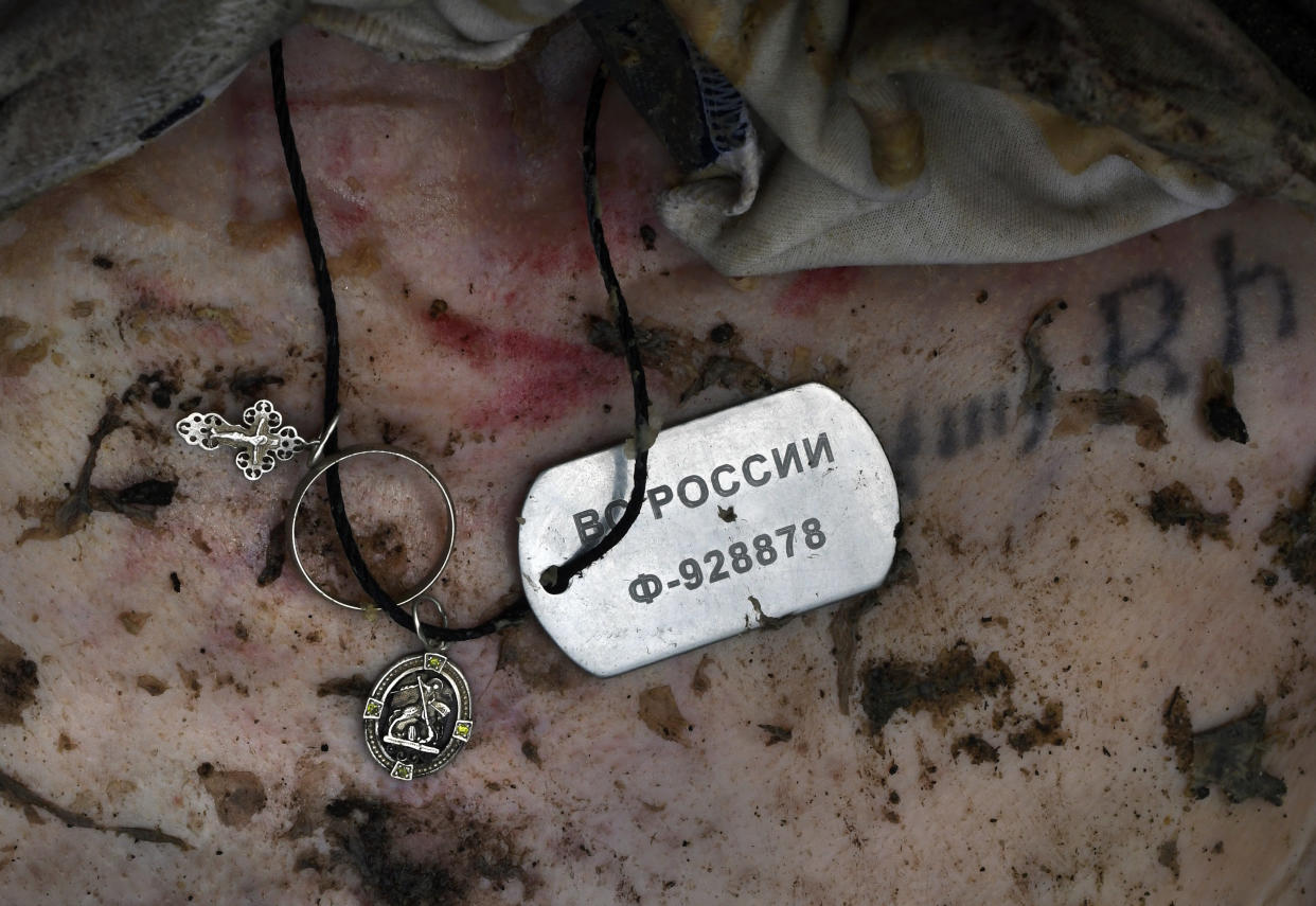 Military dogtags, a medal and a small cross lie on the body of a Russian soldier killed by Ukrainian forces in Irpin, Ukraine.