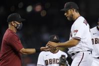 Arizona Diamondbacks starting pitcher Madison Bumgarner, right, hands the baseball over to manager Torey Lovullo as Bumgarner is taken out of the game during the fifth inning of a baseball game against the Oakland Athletics Monday, April 12, 2021, in Phoenix. (AP Photo/Ross D. Franklin)