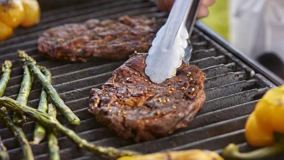 grilling rib eye steaks on the bbq with peppers and asparagus