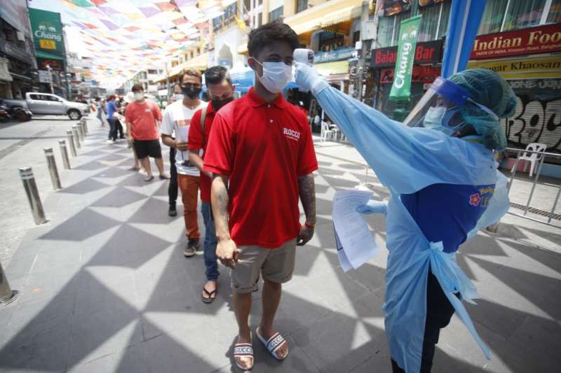 4月14日，泰國曼谷，醫護人員為排隊等待新冠肺炎篩檢的人們測量體溫（美聯社）