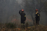 Firemen in clouds of dark smoke work on the slopes of Table Mountain in Cape Town, South Africa, Monday, April 19, 2021. Residents are being evacuated from Cape Town neighborhoods after a huge fire spreading on the slopes of the city’s famed Table Mountain was fanned by strong winds overnight and threatened houses. (AP Photo/Nardus Engelbrecht)