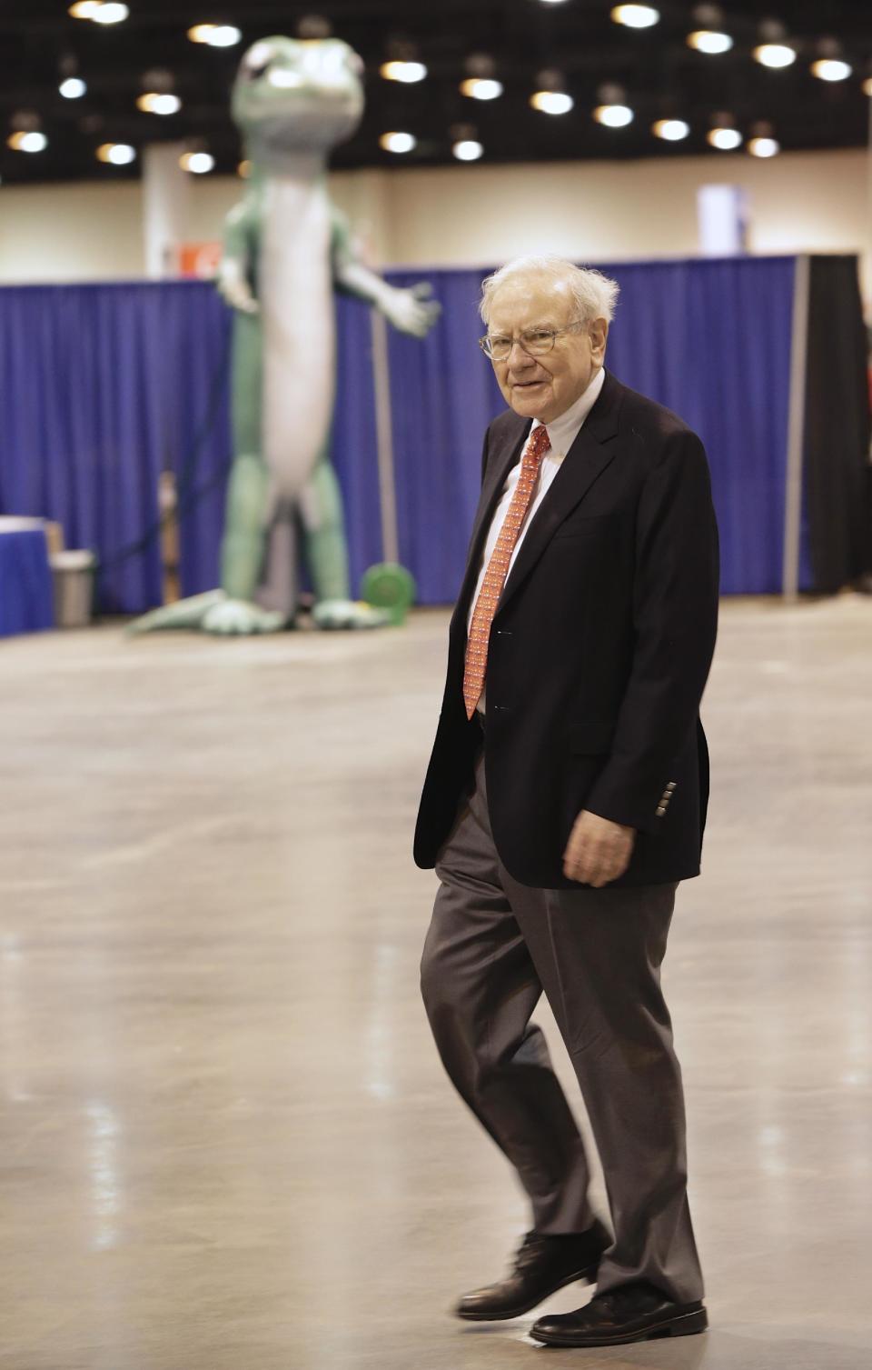 Billionaire investor Warren Buffett walks past the Geico gecko Friday, May 2, 2014, in Omaha, Neb., as he tours the exhibitor's floor where Berkshire Hathaway subsidiaries display their wares to thousands of Berkshire Hathaway shareholders who are in town for the annual shareholders meeting which takes place on Saturday. (AP Photo/Nati Harnik)