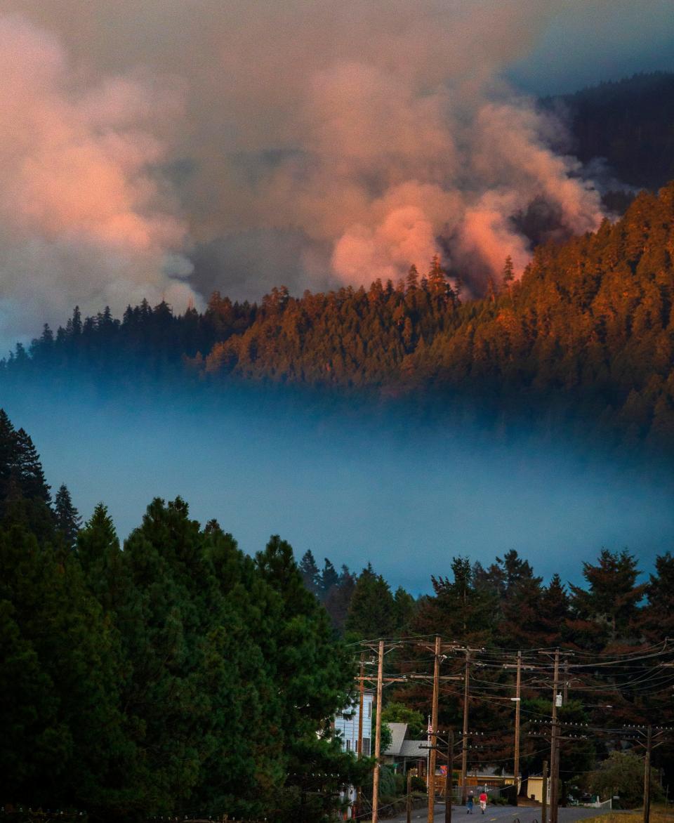 Smoke plumes rise from the Kwis Fire on the hills south of Oakridge, top, as another bank of smoke hangs in the Salmon Creek drainage below at sunset Aug. 10, 2021.