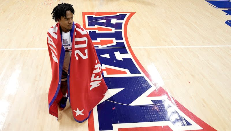 Freed-Hardeman guard Quan Lax wears the championship banner after the NAIA men's national championship college basketball game against Langston, Tuesday, March 26, 2024, in Kansas City, Mo. Freed-Hardeman won 71-67.