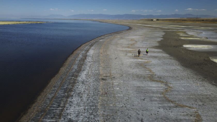 A couple walks along the receding edge of the water after record low water levels are seen at the Great Salt Lake Tuesday, Sept. 6, 2022, near Salt Lake City. A blistering heat wave is breaking records in Utah, where temperatures hit 105 degrees Fahrenheit (40.5 degrees Celsius) on Tuesday, making it the hottest September day recorded going back to 1874. (AP Photo/Rick Bowmer)