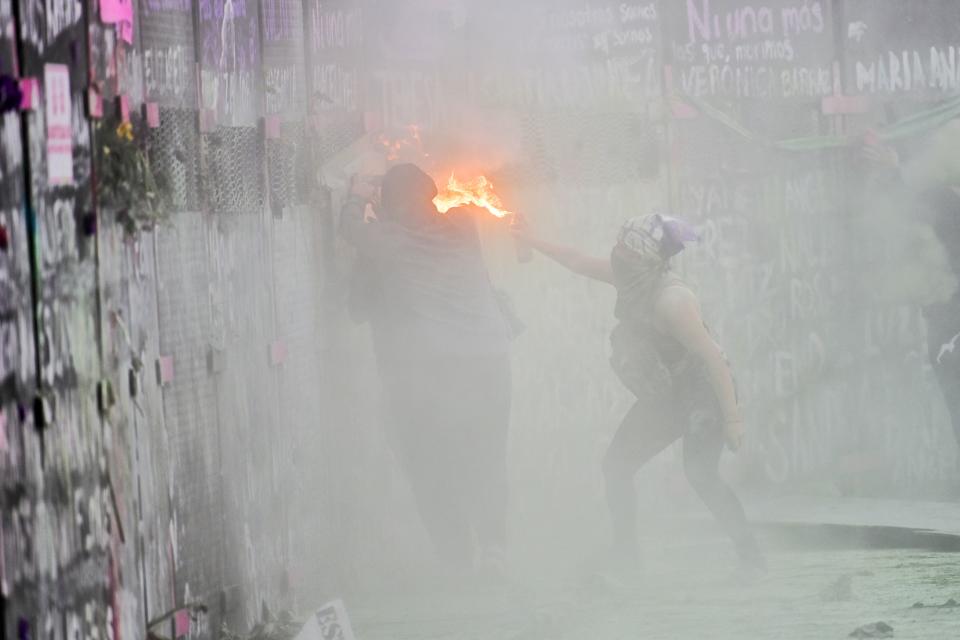 Women clash with the police, behind a fence in front of the National Palace, as they protest during a demonstration to commemorate the International Women's Day  in Mexico City, on March 8, 2021. (Photo by PEDRO PARDO / AFP) (Photo by PEDRO PARDO/AFP via Getty Images)