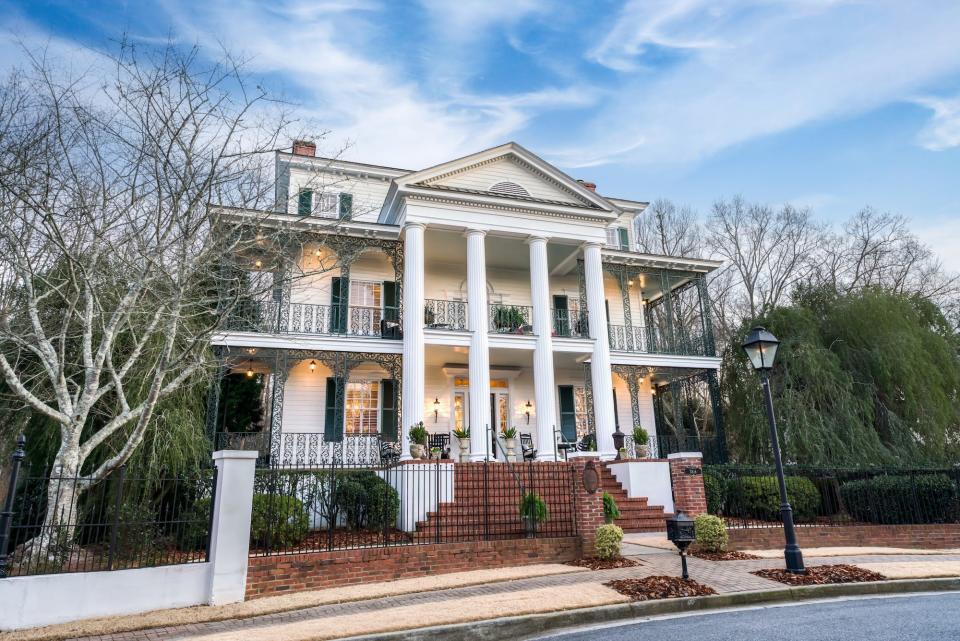 A white home with two-story patios and large pillars in the front.