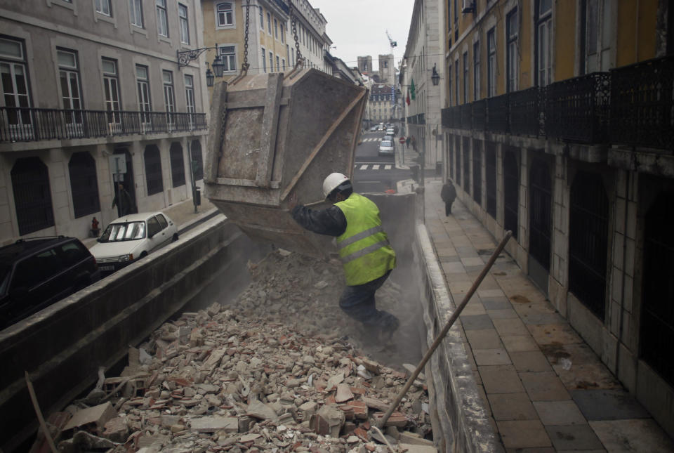 A construction worker empties a truck with debris next to the Bank of Portugal headquarters in Lisbon, Wednesday, Jan. 8, 2014. Glimmers of hope emerged Wednesday for the eurozone economy to suggest that the coming year will see the recovery gathering steam. Eurostat, the EU's statistics office, said the eurozone's unemployment rate held steady in November at a record 12.1 percent for the eighth month running after a modest 4.000 rise in the ranks of the jobless to 19.24 million. (AP Photo/Francisco Seco)