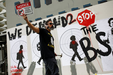 Manuel Oliver, father of Joaquin Oliver one of the victims of the mass shooting at Marjory Stoneman Douglas High School, holds up a placard as he paints a mural to commemorate the victims of the shooting and promote gun control in Los Angeles, California, U.S., April 7, 2018. REUTERS/Carlos Garcia Rawlins